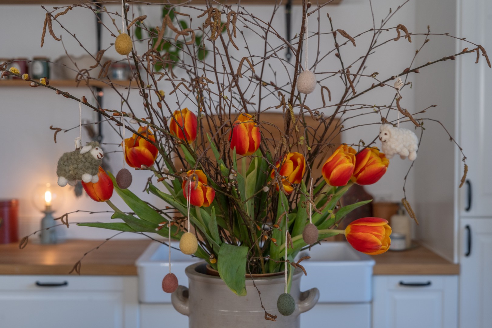Osterstrauß mit Filzeiern, Schafanhängern und Tulpen
